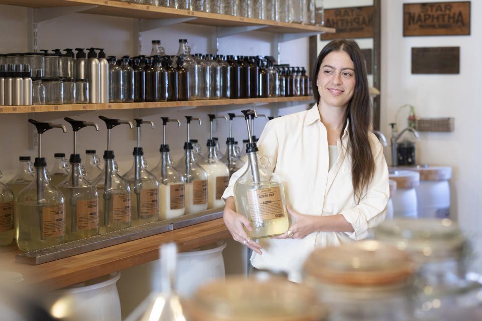 Emily Rodia, owner of Good Buy Supply, holds concentrated laundry soap that customers can pump into their own refillable containers at her store in Philadelphia, Tuesday, March 21, 2023. A growing number of companies are making bulky plastic jugs smaller and concentrating the detergent or soap. Rodia said folks of all ages are seeking concentrated detergents and other eco-friendly products. (AP Photo/Matt Rourke)