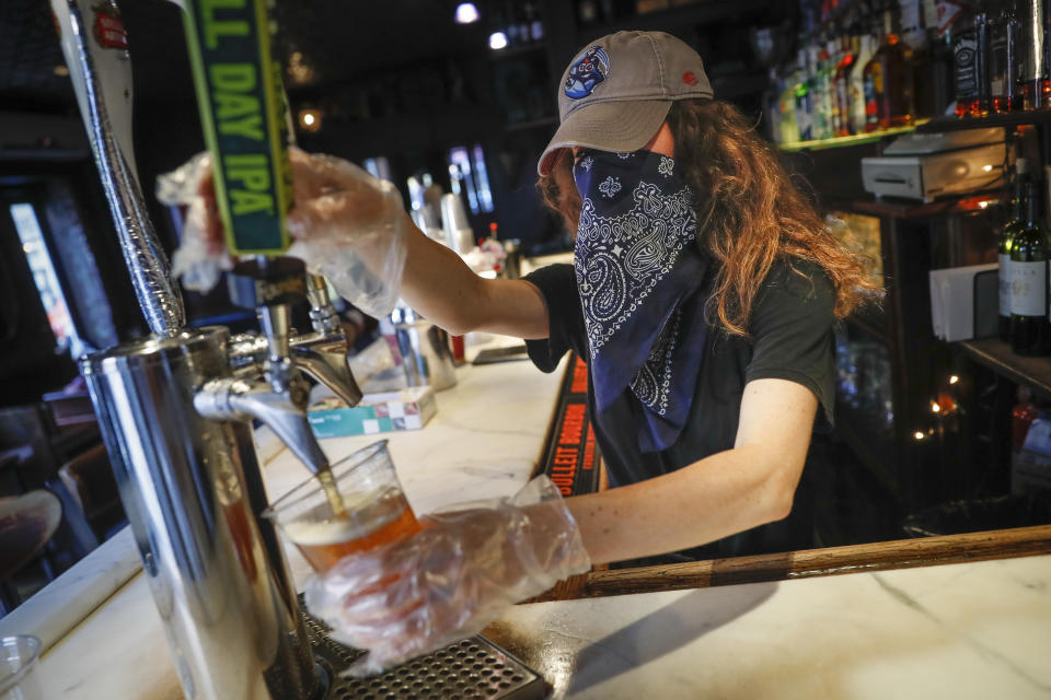 FILE - In this June 22, 2020, file photo, a bartender pours a beer for a customer at Shade Bar NYC in New York. Authorities are closing honky tonks, bars and other drinking establishments in some parts of the U.S. to stem the surge of COVID-19 infections — a move backed by sound science about risk factors that go beyond wearing or not wearing masks. (AP Photo/John Minchillo, File)