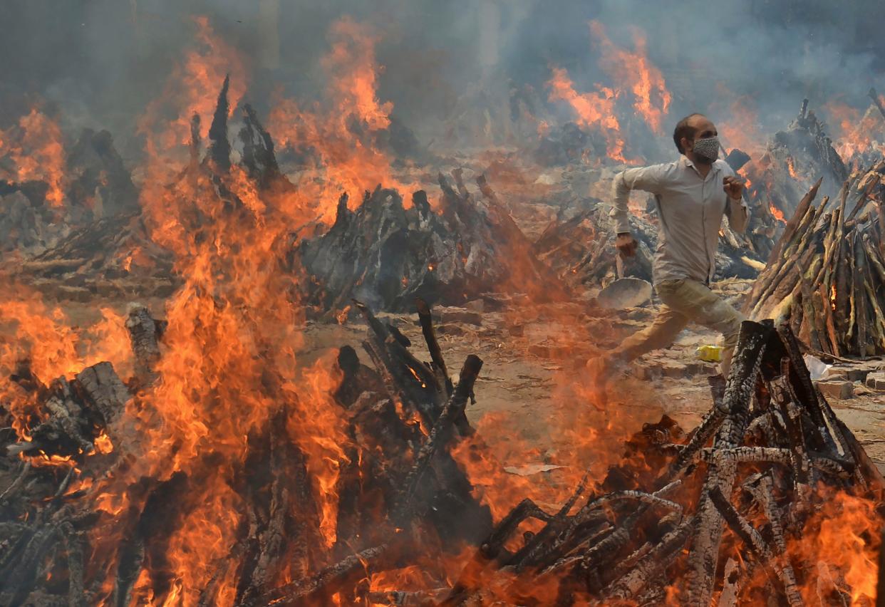 A man runs to escape heat emitting from the multiple funeral pyres of COVID-19 victims at a crematorium in the outskirts of New Delhi, India, Thursday, April 29, 2021.