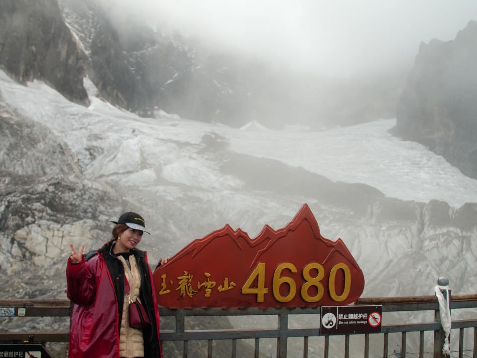 This Sept. 22, 2018 photo shows a tourist posing before the Baishui Glacier No.1 atop of the Jade Dragon Snow Mountain in the southern province of Yunnan in China. Scientists say the glacier is one of the fastest melting glaciers in the world due to climate change and its relative proximity to the Equator. It has lost 60 percent of its mass and shrunk 250 meters since 1982. (AP Photo/Sam McNeil)