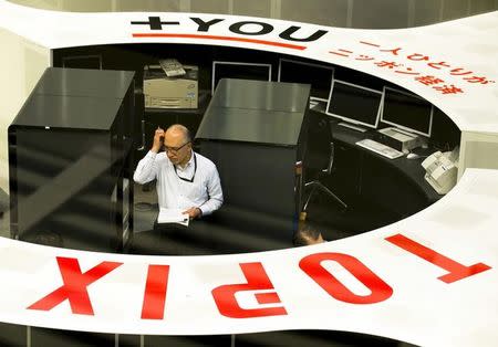 An employee looks at monitors at the Tokyo Stock Exchange (TSE) in Tokyo June 29, 2015. REUTERS/Thomas Peter