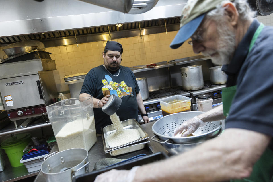 Matthew Caban, left, and Peter Woll prepare for lunch at Community Help in Park Slope, a soup kitchen and food pantry better known as CHiPS, on Friday, June 16, 2023 in New York. Charitable giving in the United States declined in 2022. The downturn in giving has led to issues at CHiPS, as it has in many charities across the country. (AP Photo/Jeenah Moon)