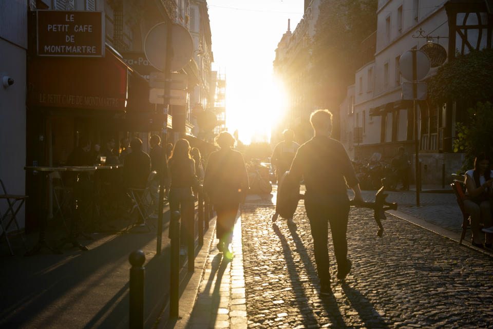 Anaïs Bulcao, second from left, and a family friend are silhouetted against the setting sun in Montmartre, Paris, on June 7, 2021. After months of restrictions and a fresh surge of infections that pushed its COVID-19 death toll past the 100,000 mark, France began easing out of lockdown in mid-May, slowly bringing life back to the streets (AP Photo/João Luiz Bulcão).