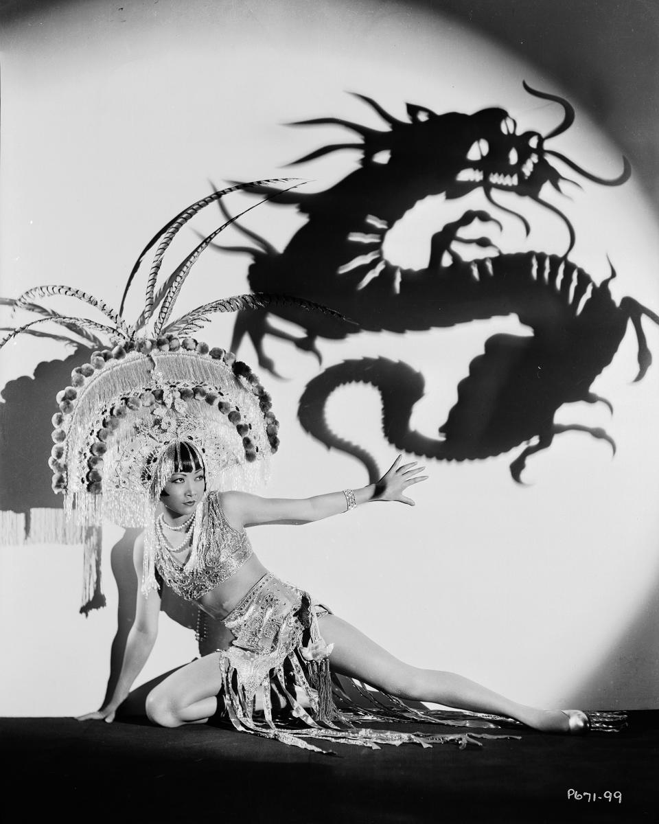 Chinese-American film star Anna May Wong wearing an exotic costume and headdress, circa 1931. Above her is a projected shadow of a dragon.<span class="copyright">John Kobal Foundation/Getty Images</span>