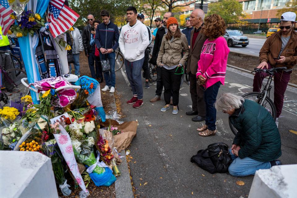 A group pauses, with some in prayer, at a makeshift memorial on a New York City bike path, on Nov. 4, 2017, that that honors victims of an attack who were stuck and killed by a rental truck driven by indicted suspect Sayfullo Saipov. Saipov, an Islamic extremist who killed eight in a New York bike path attack was convicted of federal crimes on Thursday, Jan. 26, 2023, and could face the death penalty. (AP Photo/Craig Ruttle)