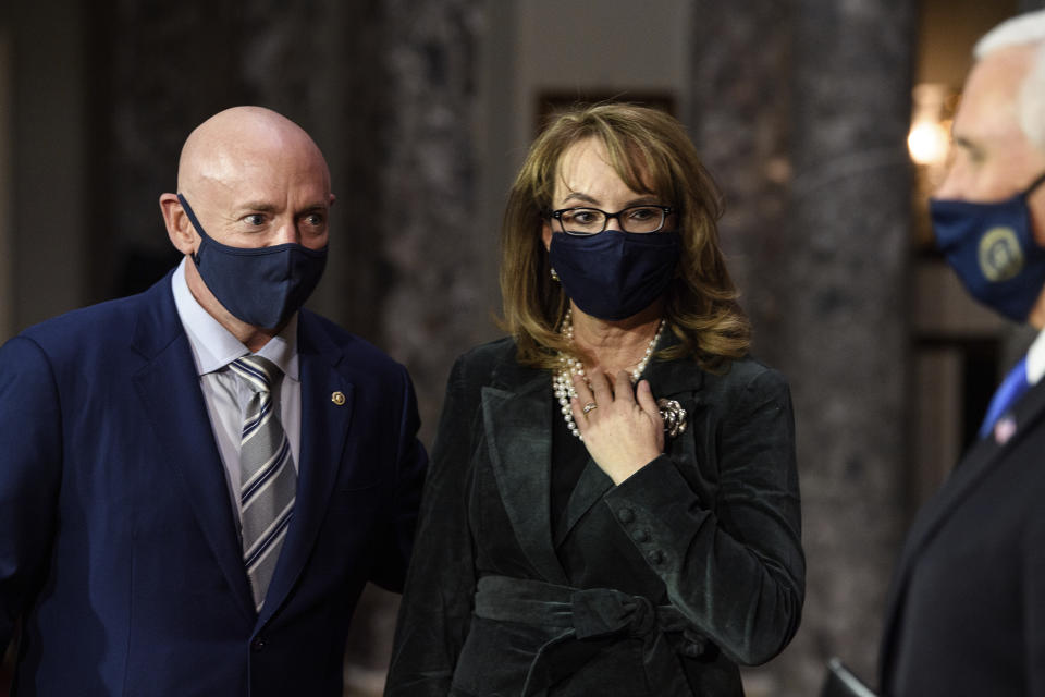 FILE - In this Dec. 2, 2020, file photo, Sen. Mark Kelly, D-Ariz., talks with his wife former Rep. Gabby Giffords, D-Ariz., and Vice President Mike Pence after participating in a re-enactment of his swearing-in on Capitol Hill in Washington. As a mob laid siege to the U.S. Capitol this week, former Rep. Gabby Giffords could only wait nervously for news about her husband, Mark Kelly, who was barely a month into his job as a newly elected senator from Arizona. A decade earlier it was Kelly enduring the excruciating wait for news about Giffords, who was shot in the head in an attempted assassination that, like Wednesday's siege, shocked the nation and prompted a reckoning about the state of politics and discourse in the United States. (Nicholas Kamm/Pool via AP, File)