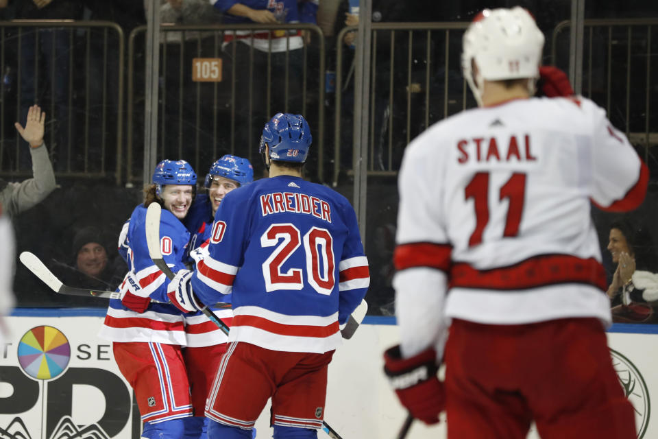 New York Rangers left wing Artemi Panarin, left, celebrates with defenseman Tony DeAngelo (77) as left wing Chris Kreider (20) approaches them with Carolina Hurricanes center Jordan Staal (11) watching after Panarin scored a goal during the second period of an NHL hockey game Friday, Dec. 27, 2019, in New York. (AP Photo/Kathy Willens)