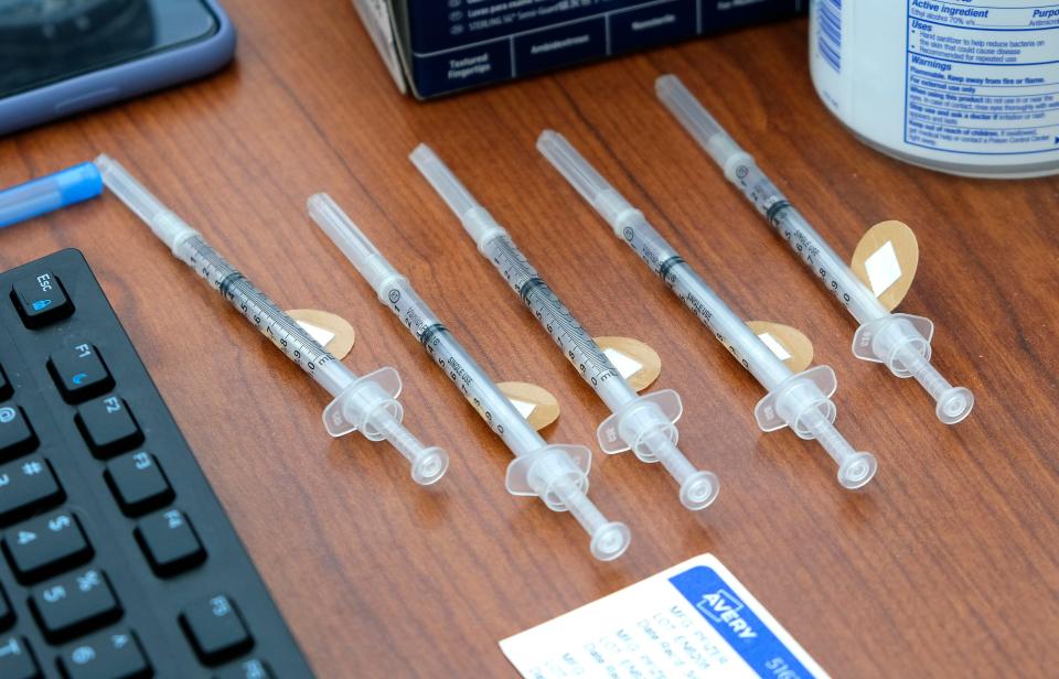 COVID-19 vaccines ready for use are shown on a desk at the Mercy vaccine clinic.