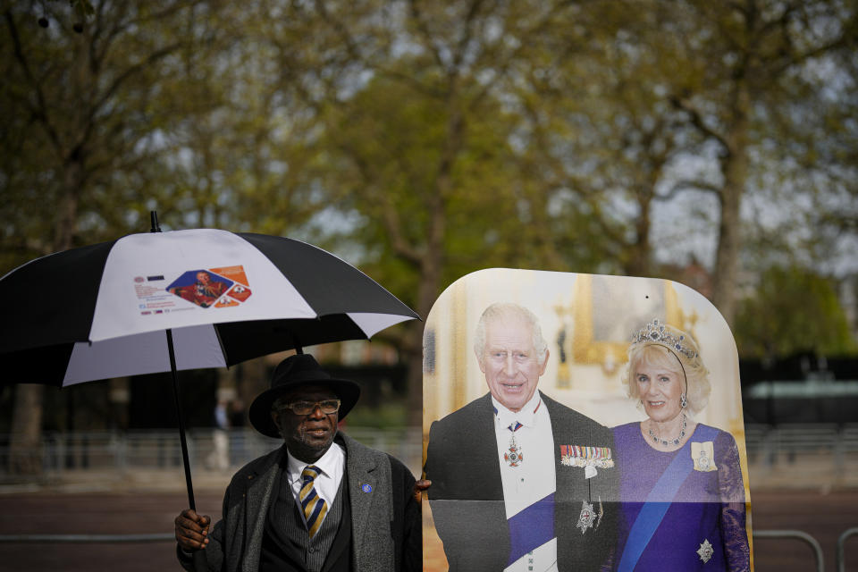 Un hombre sostiene un cartón de tamaño natural del rey Carlos III de Gran Bretaña y la reina consorte Camila en la ruta de la coronación del rey en The Mall en Londres, el jueves 4 de mayo de 2023. La coronación del rey Carlos III tendrá lugar en la Abadía de Westminster el 6 de mayo. (Foto AP/Andreea Alexandru)