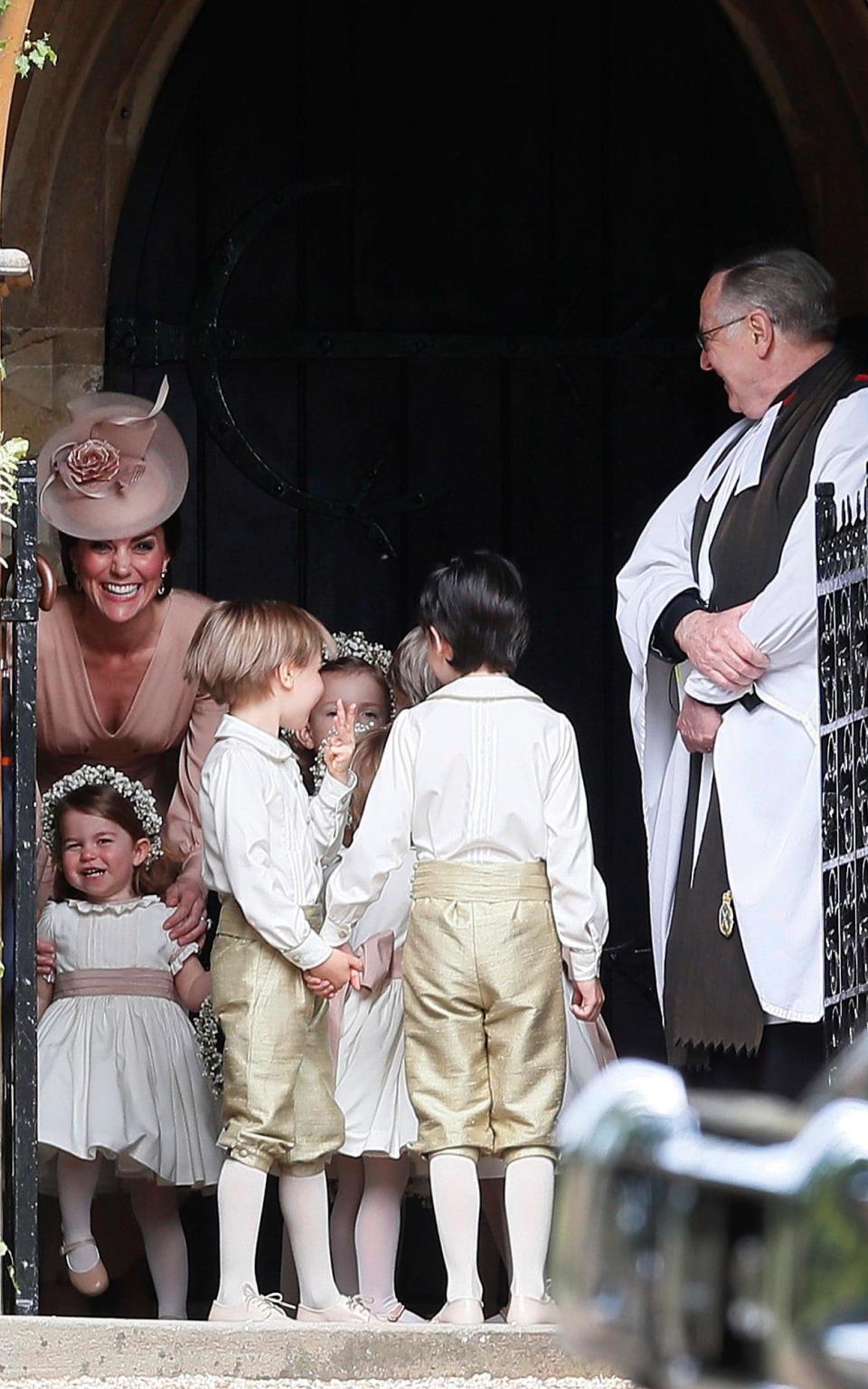 The Duchess of Cambridge smiles with bridesmaid Princess Charlotte - Credit: AP