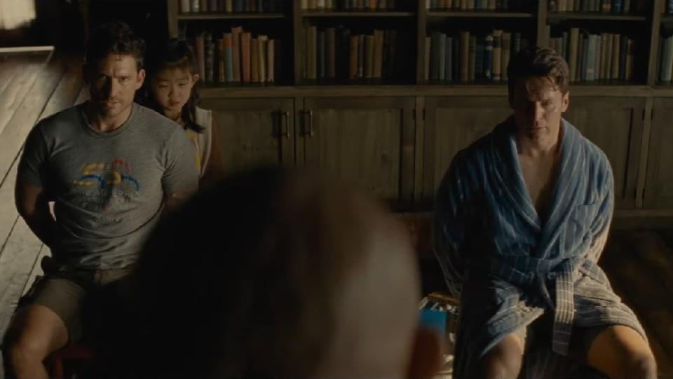 Ben Aldridge, Kristen Cui, and Jonathan Groff are tied up in chairs facing Dave Bautista whose head is large in the foreground in M. Night Shyamalan's Knock at the Cabin.