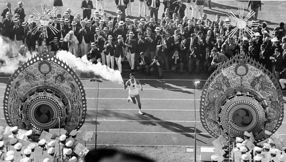 FILE - In this Oct. 10, 1964, file photo, Japanese runner Yoshinori Sakai carries the Olympic Torch during the opening ceremonies of the 1964 Summer Olympics in Tokyo. The famous 1964 Tokyo Olympics highlighted Japan’s resiliency. It was a prospering country that was showing off bullet trains, transistor radios, and a restored reputation just 19 years after devastating defeat in World War II. Now Japan and Tokyo are on display again, attempting to stage the postponed 2020 Tokyo Olympics in the midst of a once-in-a century pandemic. (AP Photo, File)