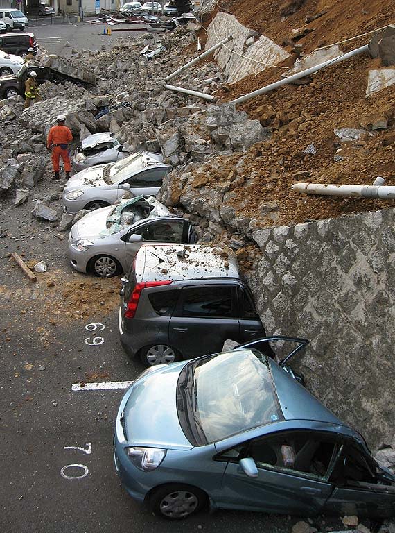 Vehicles are crushed by a collapsed wall at a carpark in Mito city in Ibaraki prefecture on March 11, 2011 after a massive earthquake rocked Japan. massive 8.9-magnitude earthquake hit Japan on March 11, unleashing a monster 10-metre high tsunami that sent ships crashing into the shore and carried cars through the streets of coastal towns. AFP PHOTO / JIJI PRESS