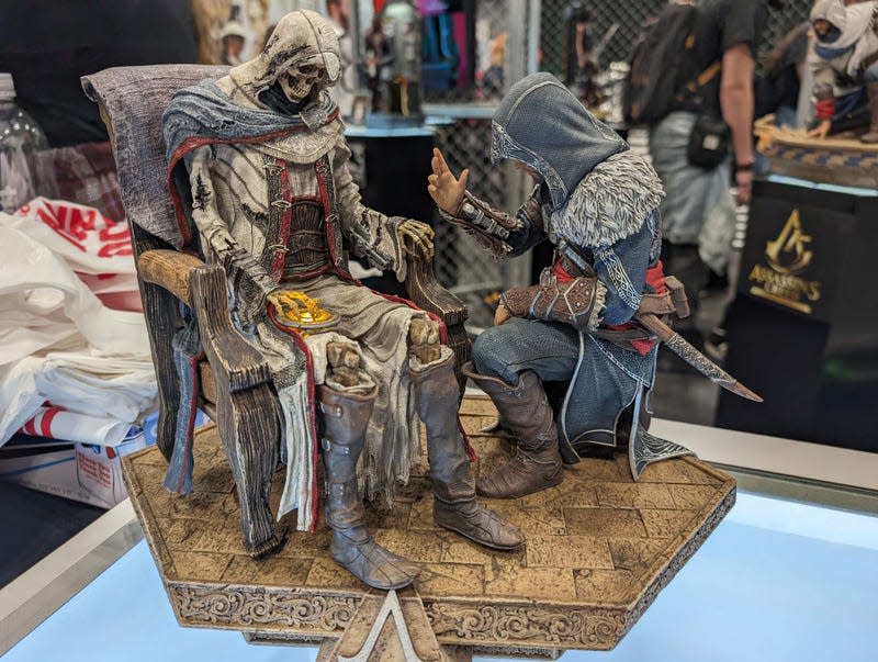 A statue of a skeleton and Assassin are on display.