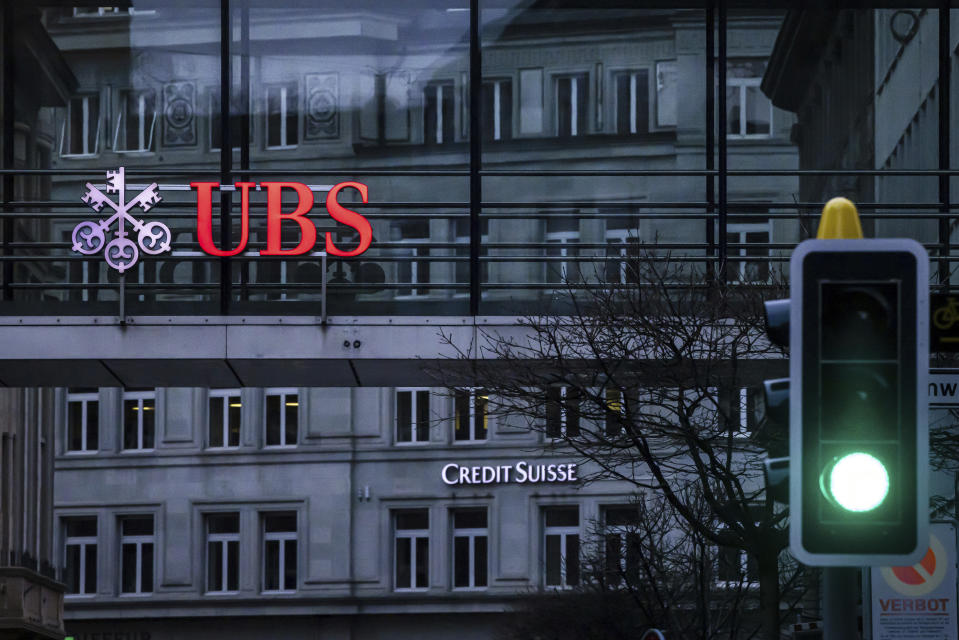 A traffic light signals green in front of the logos of the Swiss banks Credit Suisse and UBS in Zurich, Switzerland, Sunday March 19, 2023. (Michael Buholzer/Keystone via AP)