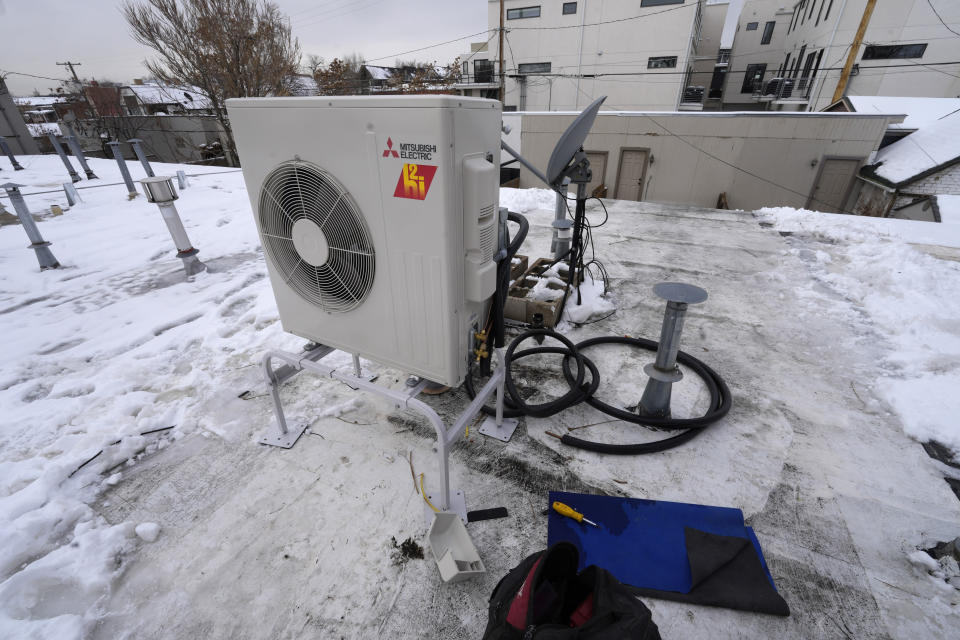 A condenser sits on the roof during the installation of a heat pump in an 80-year-old rowhouse Friday, Jan. 20, 2023, in northwest Denver. (AP Photo/David Zalubowski)