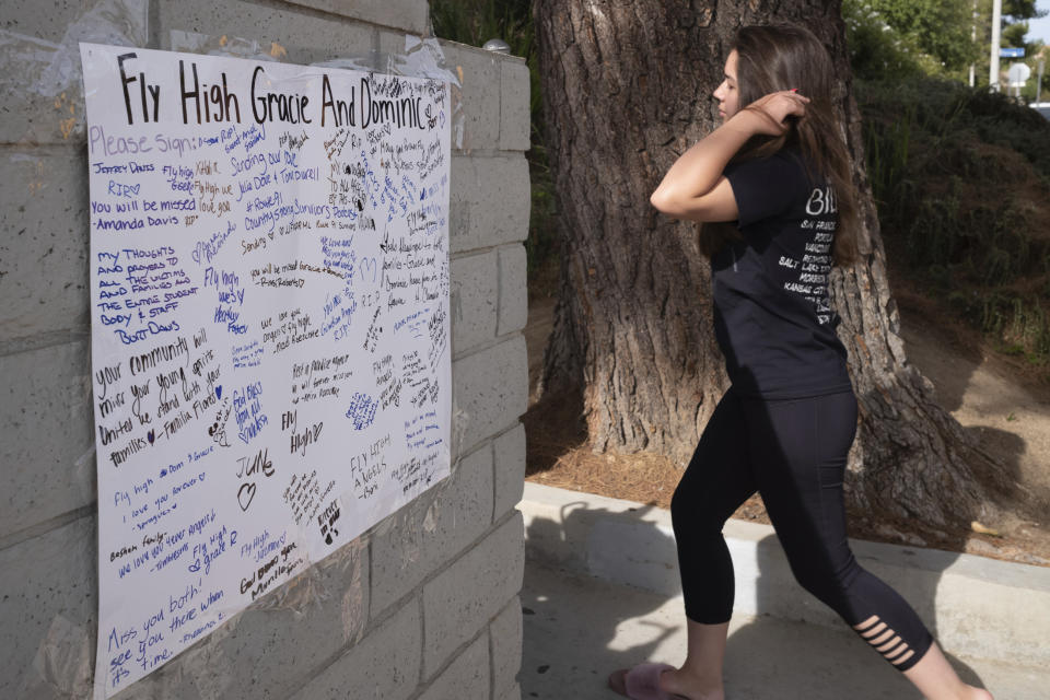 Saugus high students walk past a memorial with well wishes placed up for Gracie Muehlberger and Dominic Blackwell Tuesday, Nov. 19, 2019. Students were allowed back to collect their belongings left behind after the tragic shooting last Thursday. Classes will resume at the high school on Dec. 2. (David Crane/The Orange County Register via AP)