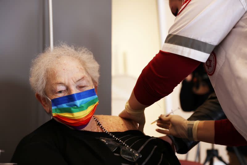 A elderly woman receives a booster shot of her vaccination against the coronavirus disease (COVID-19) at an assisted living facility, in Netanya