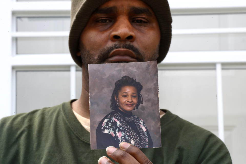 Jamon Jordan poses with a photo of his mother, Jacquelynne Jordan, in Detroit, Friday, April 24, 2020. Jamon Jordan could not mourn his mother in the traditional way. At Jacquelynne Jordan's memorial in early April, there were just seven people. No hugs. No traditional dinner where family members could gather to honor the 66-year-old matriarch's memory after she died from the new coronavirus. (AP Photo/Paul Sancya)