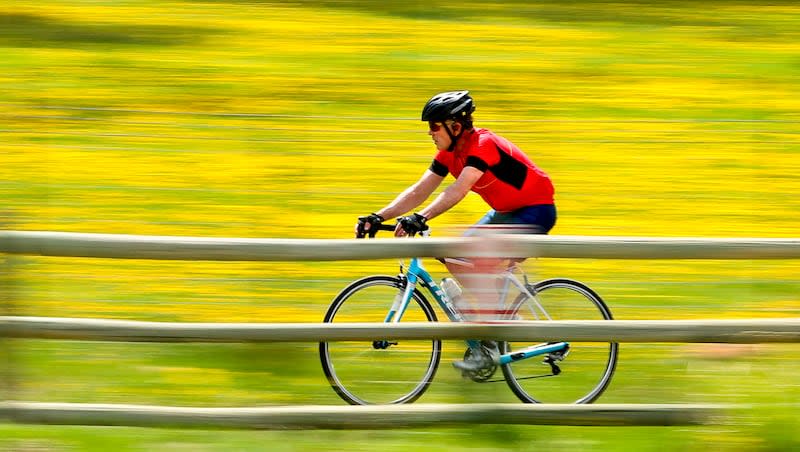 A biker zips past a field of dandelions while riding on the paved trail system in Park City on May 11, 2020. The Biden administration has a new grant program that for the first time authorizes not just building trails but also connecting existing ones.