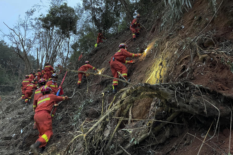 In this photo released by Xinhua News Agency, rescuers conduct search operations at the site of a plane crash in Tengxian County in southern China's Guangxi Zhuang Autonomous Region, Tuesday, March 22, 2022. Mud-stained wallets. Bank cards. Official identity cards. Some of the personal effects of 132 lives presumed lost were lined up by rescue workers scouring a remote mountainside Tuesday for the wreckage of a China Eastern plane that one day earlier inexplicably fell from the sky and burst into a huge fireball. (Zhou Hua/Xinhua via AP)