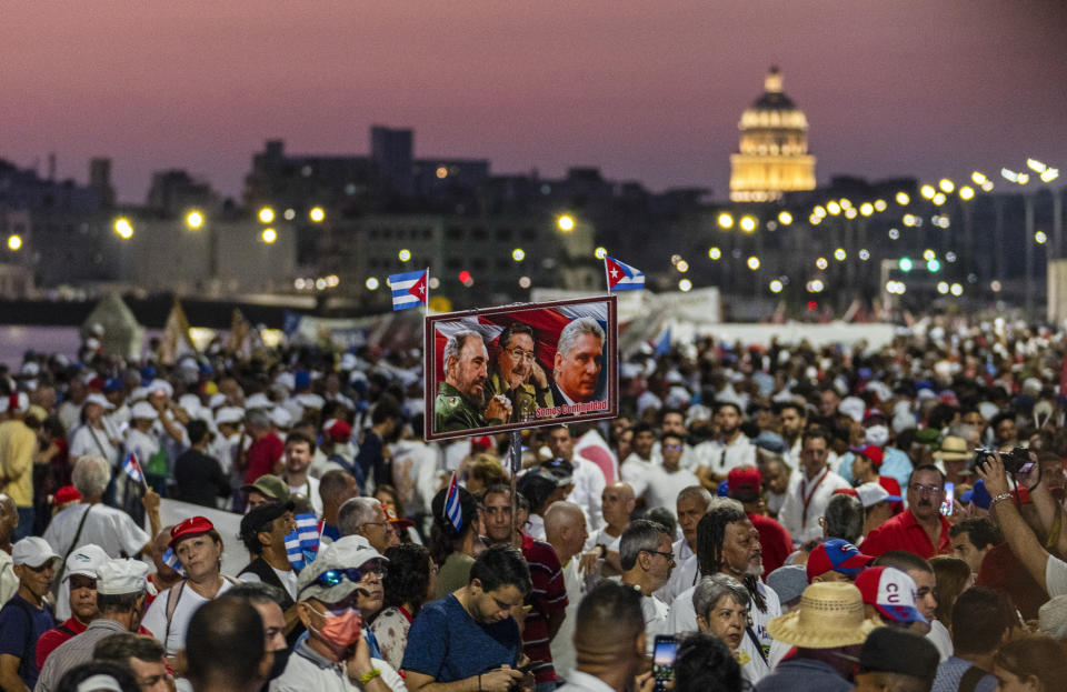 Personas sostienen fotografías del presidente cubano Miguel Díaz-Canel, el expresidente cubano Raúl Castro y el difunto Fidel Castro durante una celebración del Día del Trabajador en La Habana, Cuba, el viernes 5 de mayo de 2023. La celebración del 1 de mayo fue pospuesta cuatro días por problemas climatológicos y las carencias de combustibles en la isla. (Foto AP/Ramón Espinosa)