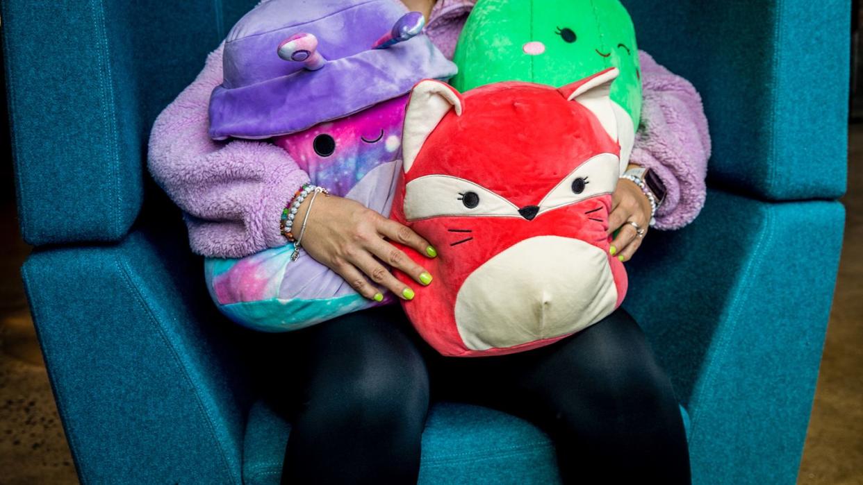 a person holding three squishmallows