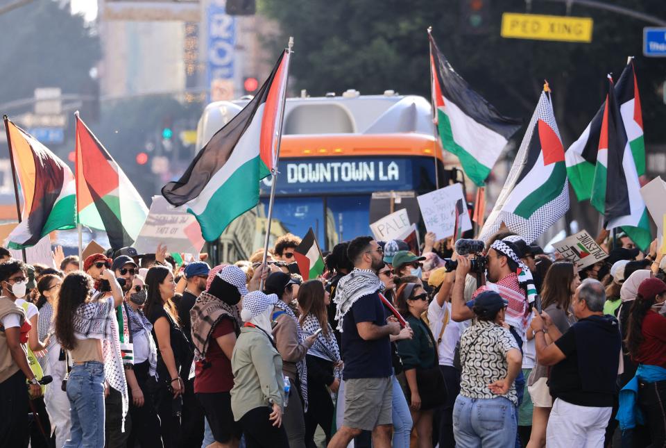 Protesters waving the Palestinian flag march in front of a bus in Los Angeles, California.