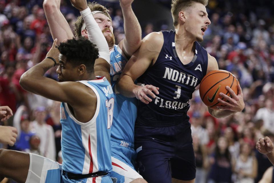 Carter Hendricksen of the University of North Florida (3) pulls a rebound away from Malachi Smith (left) and Drew Timme (center) during Monday's game against Gonzaga in Spokane, Wash.