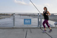 In this April 6, 2020 photo, a jogger on the Bob Kerrey pedestrian bridge over the Missouri River is about to cross over from Omaha, Neb., to Council Bluffs, Iowa. While most governors have imposed stay-at-home orders to slow the spread of the coronavirus, leaders of a handful of states have rejected such action. (AP Photo/Nati Harnik)