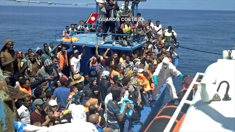 Migrants wait to be rescued from an overcrowded boat off the coast of Libya on August 23, 2015