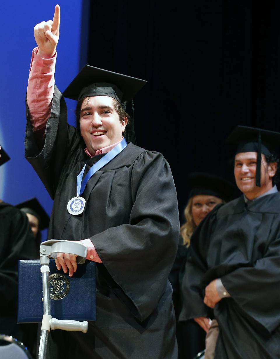 Boston Marathon bombing survivor Jeff Bauman reacts after receiving an honorary degree as Carlos Arredondo, right, looks on during commencement ceremonies for Fisher College in Boston, Saturday, May 10, 2014. Bauman lost his legs in the attack. Bauman and Arrendondo, who saved Bauman's life the day of the bombing, each gave graduation speeches and were awarded honorary degrees during the ceremony. (AP Photo/Michael Dwyer)