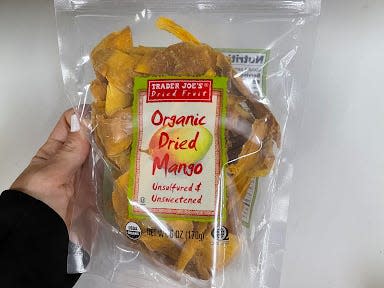 hand holding package of trader joe's dried mango