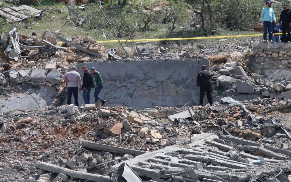 People gather around a destroyed building targeted by Israeli air strikes on the village of Nabi Sheet in the Baablbek