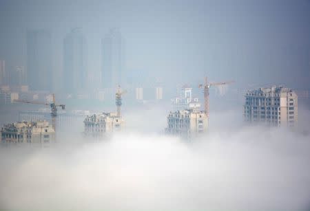 Buildings under construction are seen during a hazy day in Rizhao, Shandong Province, China, March 15, 2016. REUTERS/Stringer/Files