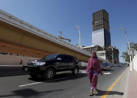 The construction site of the Bharia Icon 62 story building is seen in the background as a woman walks along a street in Karachi, Pakistan, February 9, 2016. REUTERS/Akhtar Soomro