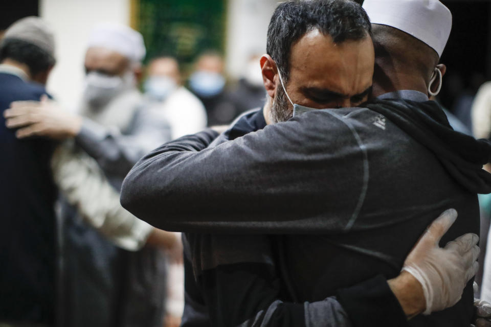 Tariq Aziz, al centro, hermano de Mohammad Altaff, que murió de COVID-19, recibe un abrazo al término de las oraciones en memoria del fallecido el domingo 17 de mayo de 2020, en la Funeraria Musulmana Al-Rayaan en el distrito de Brooklyn, en Nueva York. (AP Foto/John Minchillo)