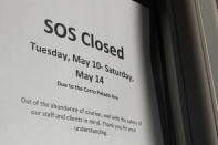 A storefront window announces a weeklong work hiatus on Thursday, May 12, 2022, as residents of Los Alamos, N.M., prepared to possibly flee a wildfire as it crept within a few miles of the city and companion national security laboratory. Scientists at Los Alamos National Laboratory are using supercomputers and ingenuity to improve wildfire forecasting and forest management amid drought and climate change in the American West. (AP Photo/Morgan Lee)