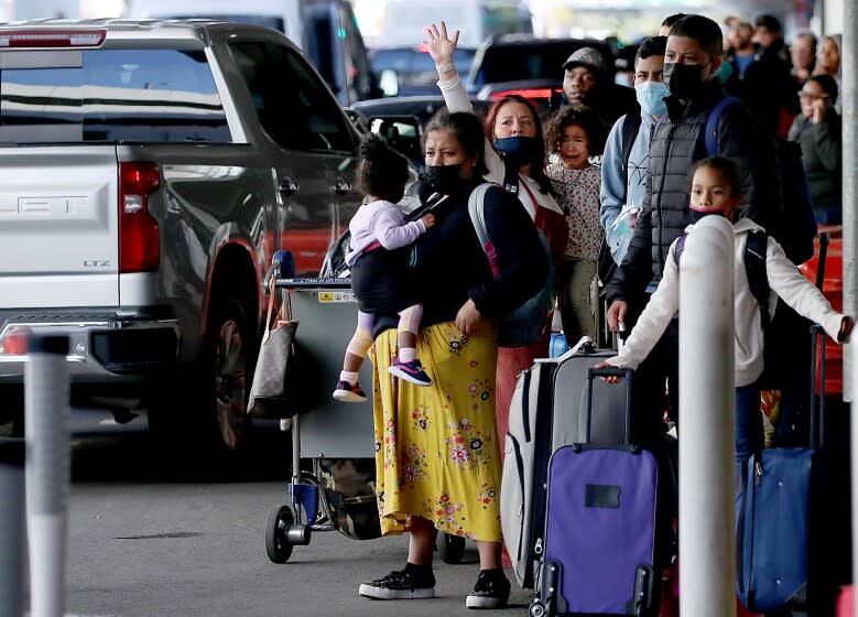 LOS ANGELES, CA. - DEC 24, 2021. Travelers arriving at LAX wait for transportation away from the airport on Friday, Dec. 24, 2021. The Omicron variant of the coronavirus has swept across the world as millions of travelers are on the move for the holidays. Thousands of flights worldwide were canceled on Friday because of the fast-spreading virus. (Luis Sinco / Los Angeles Times)