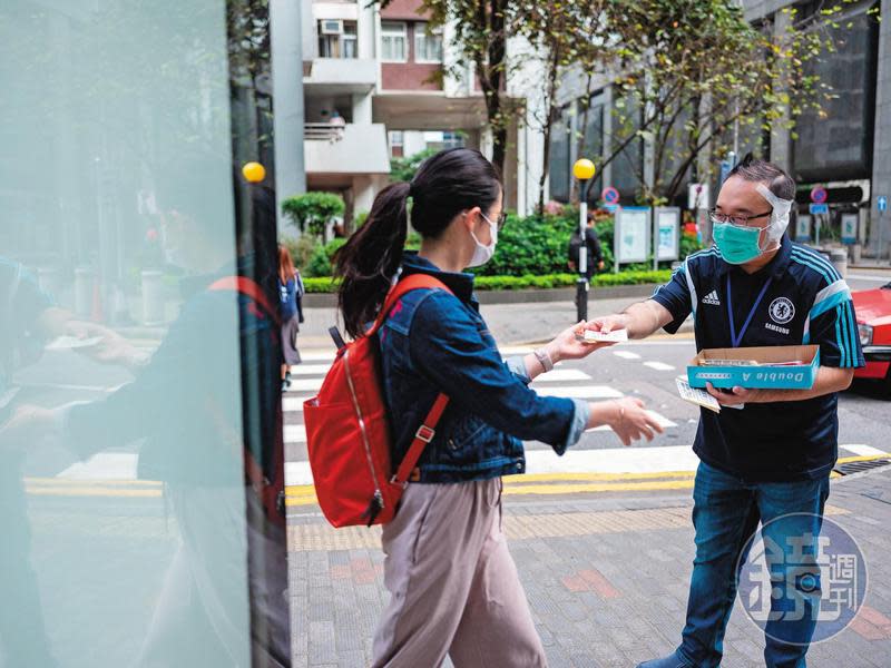 趙家賢（右）被咬掉的耳傷未癒，在服務選民時還曾遭惡言相向。即便如此，他仍黏著紗布上街，與選民互動。圖為趙家賢發給市民自製的福曆。