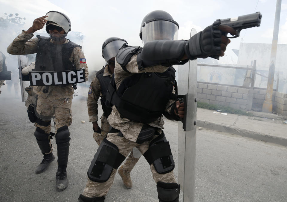 A police officer aims his weapon after demonstrators calling for the resignation of President Jovenel Moise broke through their lines, in Port-au-Prince, Haiti, Friday, Oct. 4, 2019. After a two-day respite from the recent protests that have wracked Haiti's capital, opposition leaders urged citizens angry over corruption, gas shortages, and inflation to join them for a massive protest march to the local headquarters of the United Nations. (AP Photo/Rebecca Blackwell)