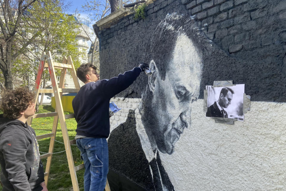 Austrian graffiti duo Joel Gamnou paint a picture of Alexei Navalny on a wall in Vienna, Austria, Wednesday, March 27, 2024. Two large portraits of the late Russian opposition leader Alexei Navalny have been spray-prainted on a property owned by the family of a former Czech foreign minister behind a monument to Soviet soldiers in Vienna. (AP Photo/Philipp-Moritz Jenne)