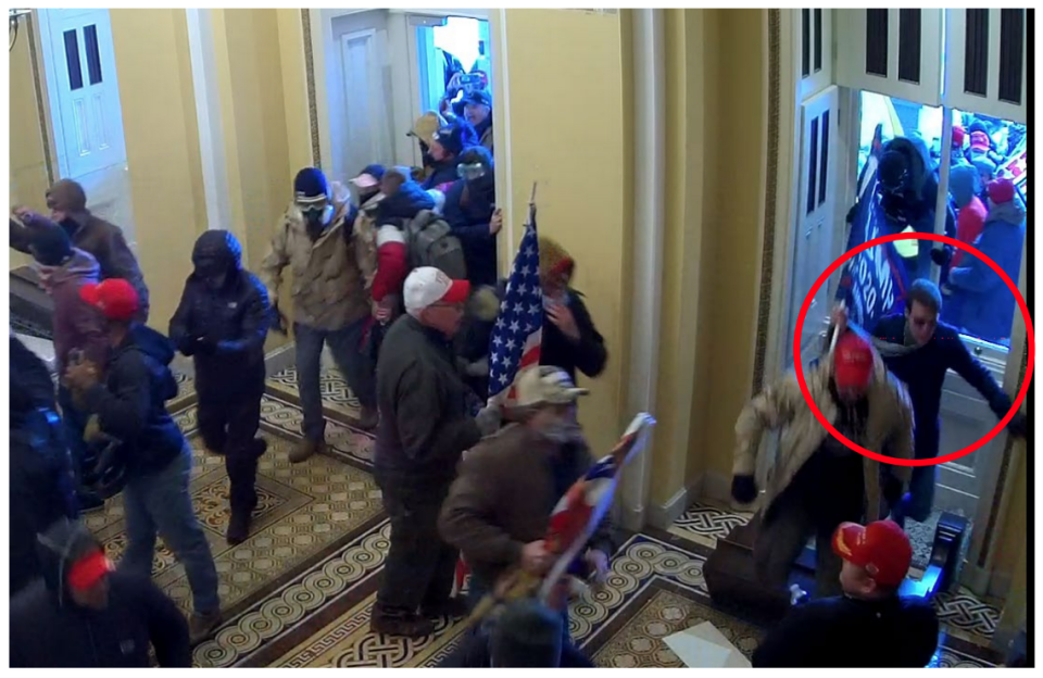 In this image filed with an FBI arrest warrant, a man believed to be Matthew Mark Wood of Reidsville, N.C., storms through a broken window, Trump flag in tow, at the U.S. Capitol in Washington on Jan. 6, 2021.