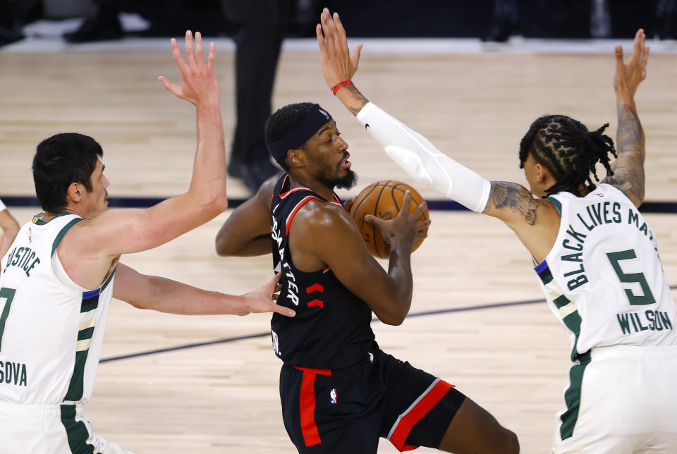 Toronto Raptors' Paul Watson #1 of the Toronto Raptors goes up for a shot while pressured byMilwaukee Bucks' Ersan Ilyasova, left, and D.J. Wilson during the fourth quarter of an NBA basketball game Monday, Aug. 10, 2020, in Lake Buena Vista, Fla. (Mike Ehrmann/Pool Photo via AP)