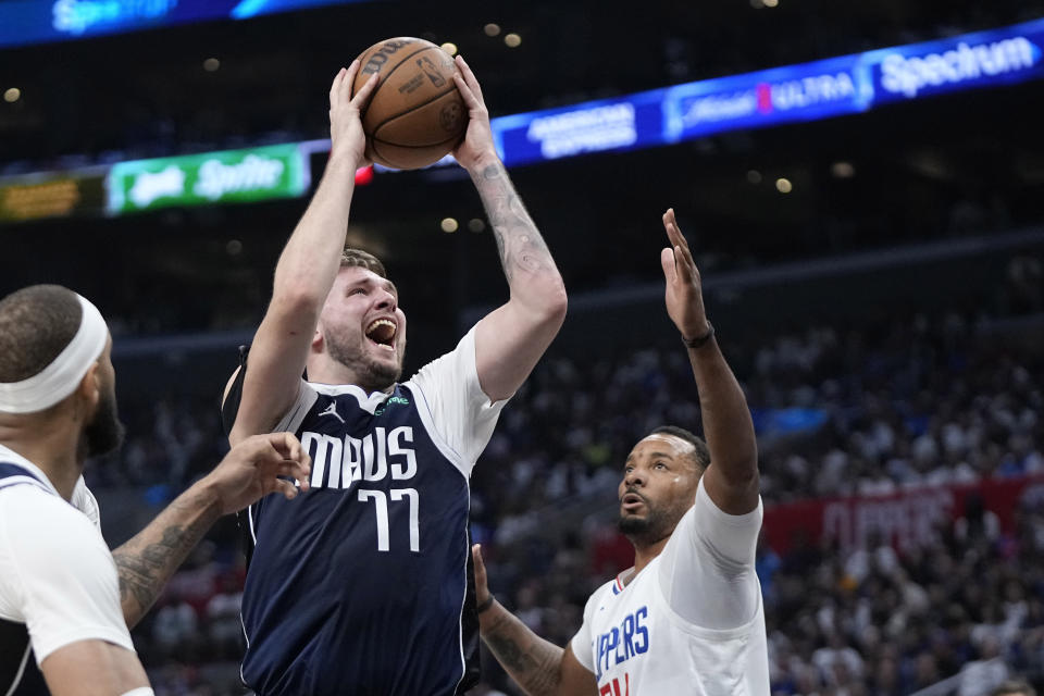 FILE - Dallas Mavericks guard Luka Doncic, center, shoots as Los Angeles Clippers guard Norman Powell, right, defends during the second half in Game 5 of an NBA basketball first-round playoff series Wednesday, May 1, 2024, in Los Angeles. Doncic, Nikola Jokic and Shai Gilgeous-Alexander are the three finalists for the NBA MVP Award that will be announced Wednesday, May 8, 2024. (AP Photo/Mark J. Terrill, File)