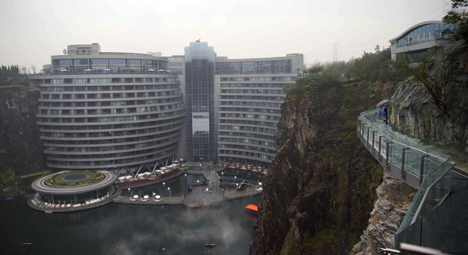 Visitors walk near the Intercontinental Shanghai Wonderland Hotel in Songjiang district of Shanghai, east China, Thursday, Jan. 15, 2018. The 18-story hotel has been built into the side of a huge hole in the ground left by a former put mine with sixteen of its floors below ground level. (AP Photo)