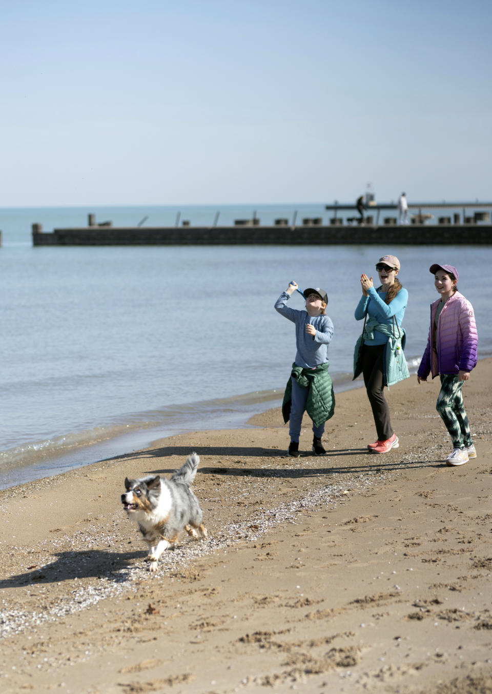In this photo provided by Madeleine Beck, Maria Colavincenzo, center, strolls on the beach of Lake Michigan in Chicago, Sunday, Feb. 25, 2024, with her children, 7-year-old Patrick Galvin, left, and 11-year-old Eloise Galvin, right, and their dog, Greta. They joined throngs of people who turned out to enjoy warmer-than-usual weather. While temperatures usually hover around freezing in late February, they reached into the 60s in Chicago and other Midwest cities. (Madeleine Beck via AP)