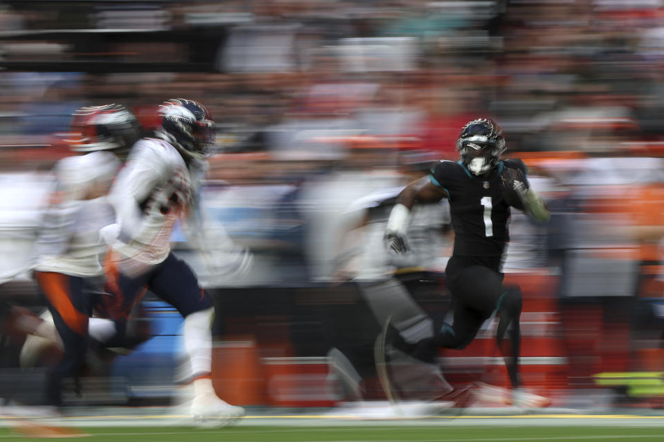 Jacksonville Jaguars running back Travis Etienne Jr. (1) , right, runs with the ball during the NFL football game between Denver Broncos and Jacksonville Jaguars at Wembley Stadium in London, Sunday, Oct. 30, 2022. (AP Photo/Ian Walton)