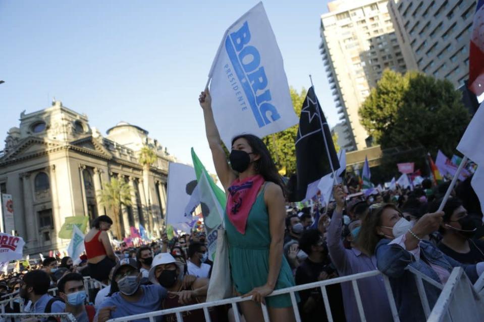 Mujer con bandera con nombre de Boric entre la multitud en Santiago de Chile el 19 de diciembre de 2021.