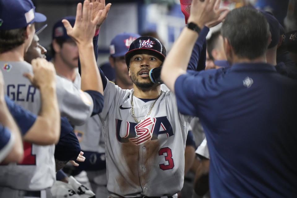 Mookie Betts (3) es felicitado por sus compañeros tras anotar una carrera para Estados Unidos ante Venezuela en los cuartos de final del Clásico Mundial de béisbol, el 18 de marzo de 2023, en Miami. (AP Foto/Wilfredo Lee)